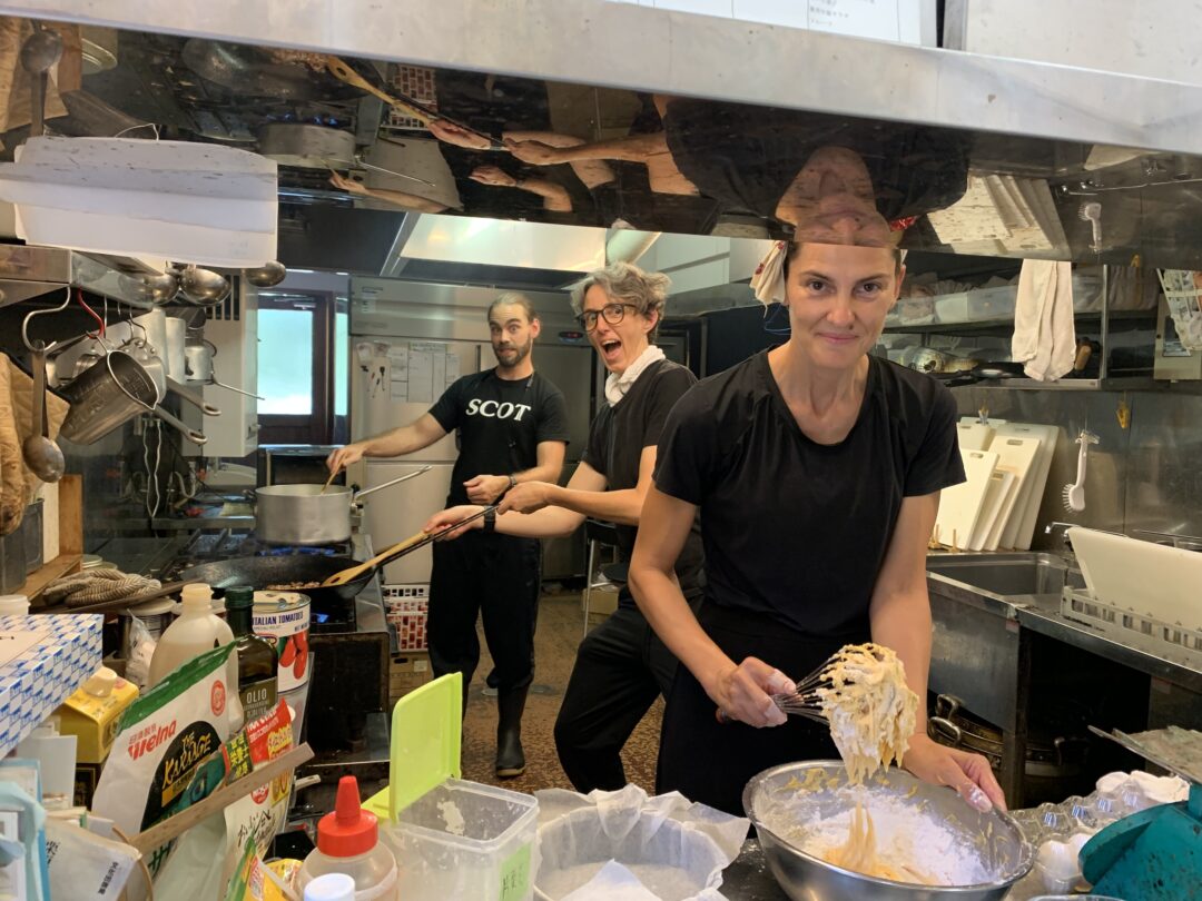 un uomo e due donne in una cucina stanno preparando pitti tipici della propria tradizione culinaria