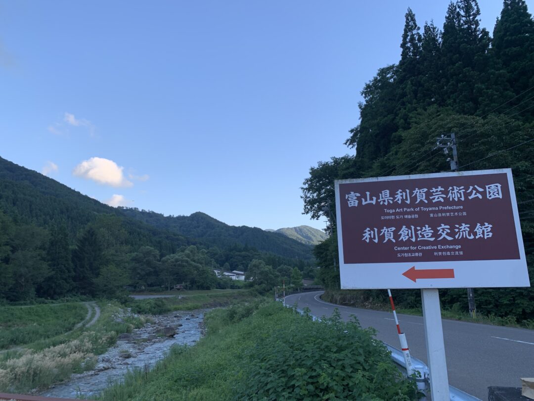 il cartello che indica l'ingresso al Toga Art Park. Sullo sfondo la valle del fiume kamimomose all'imbrunire