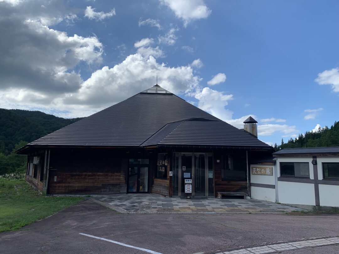 visuale sterna di un piccolo edificio di chiara architettura giapponese immerso tra verdi colline