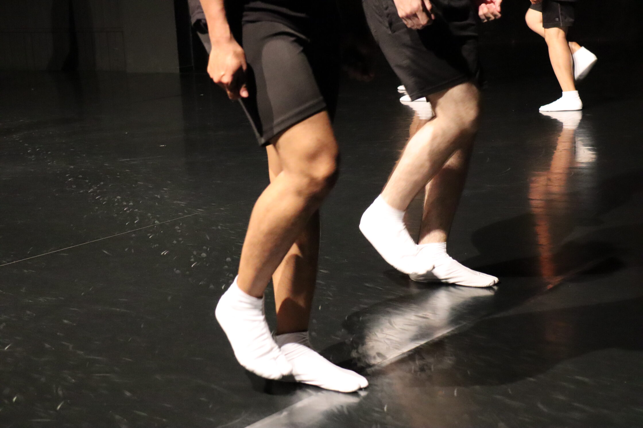 Le gambe di tre persone che indossano tali bianchi ed eseguono il movimento dello stomping